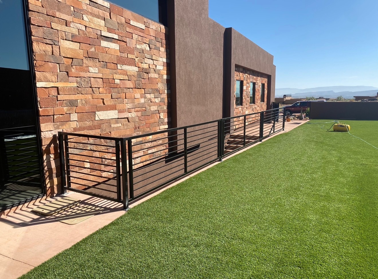 Modern black steel railing with horizontal bars running along the side of a contemporary desert home with stacked stone veneer in St. George, Utah