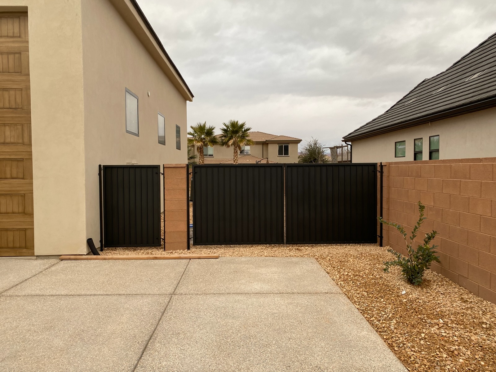 Black steel double swing RV gate and matching walk-through gate with vertical ribbed privacy panels next to a concrete driveway in St. George, Utah